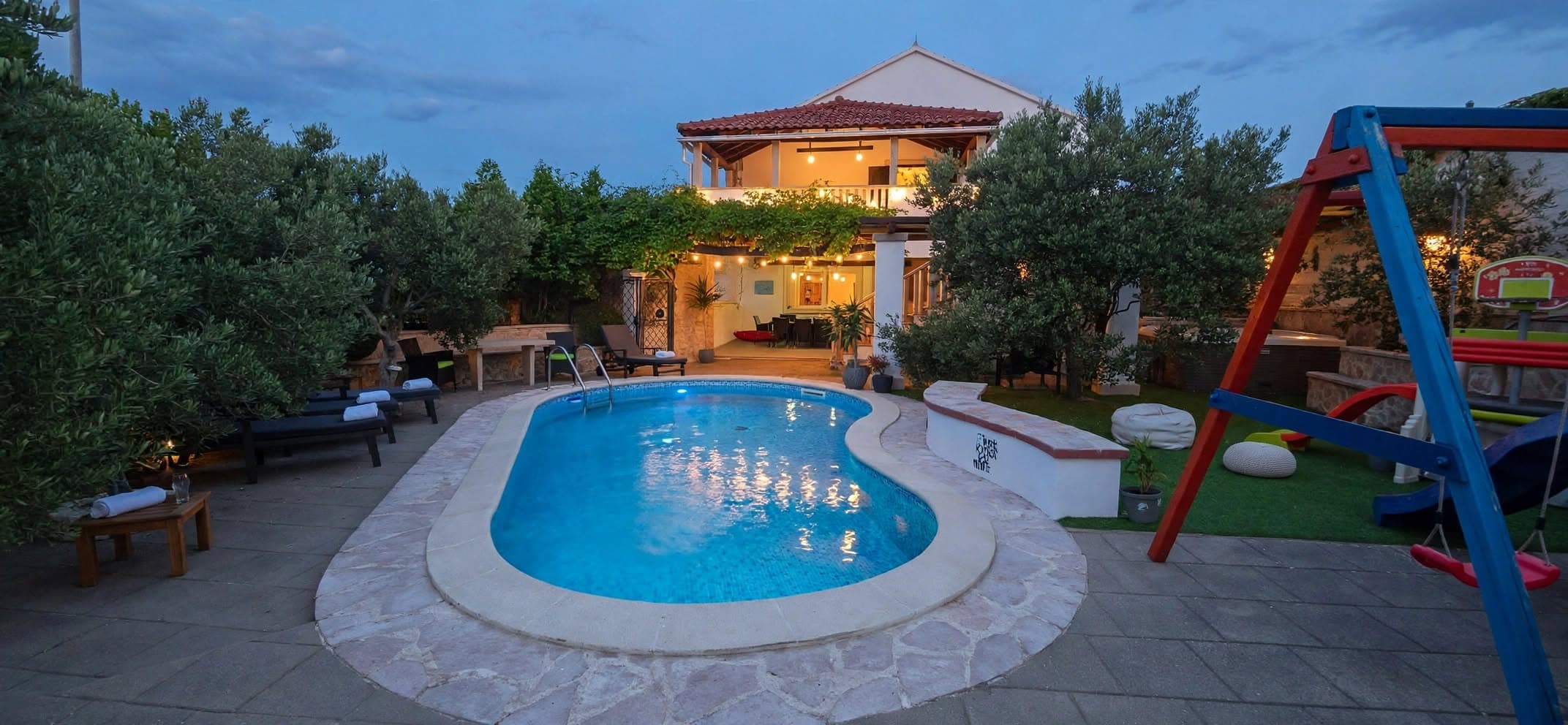 The pool and the house in the evening, with a playground on the side