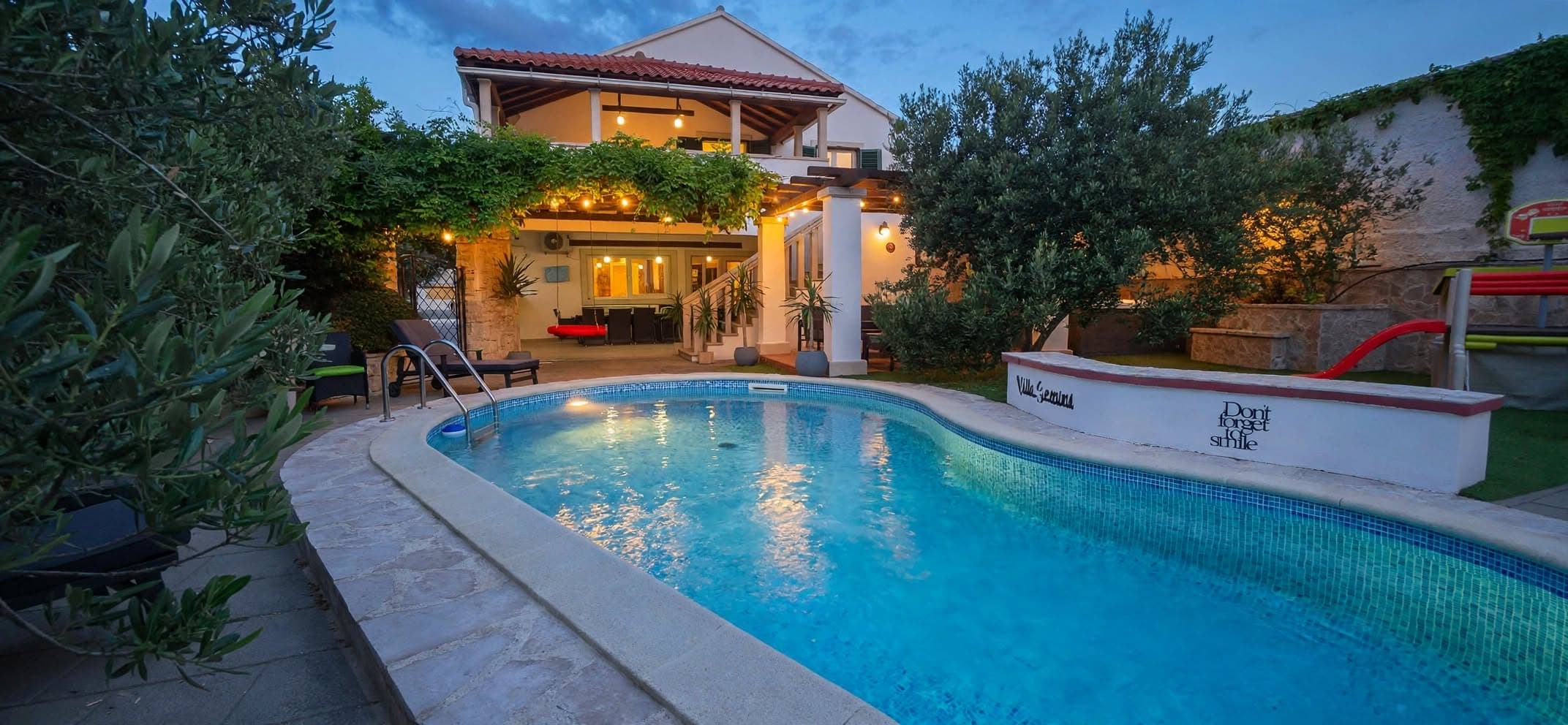Villa Gemini at dusk with the lit pool in front of the house